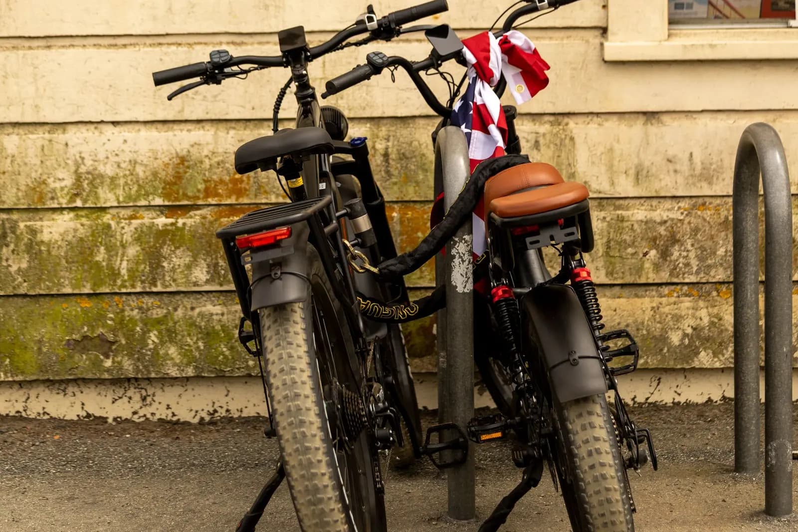 Twee e-bikes vastgezet aan een paal tegen een muur