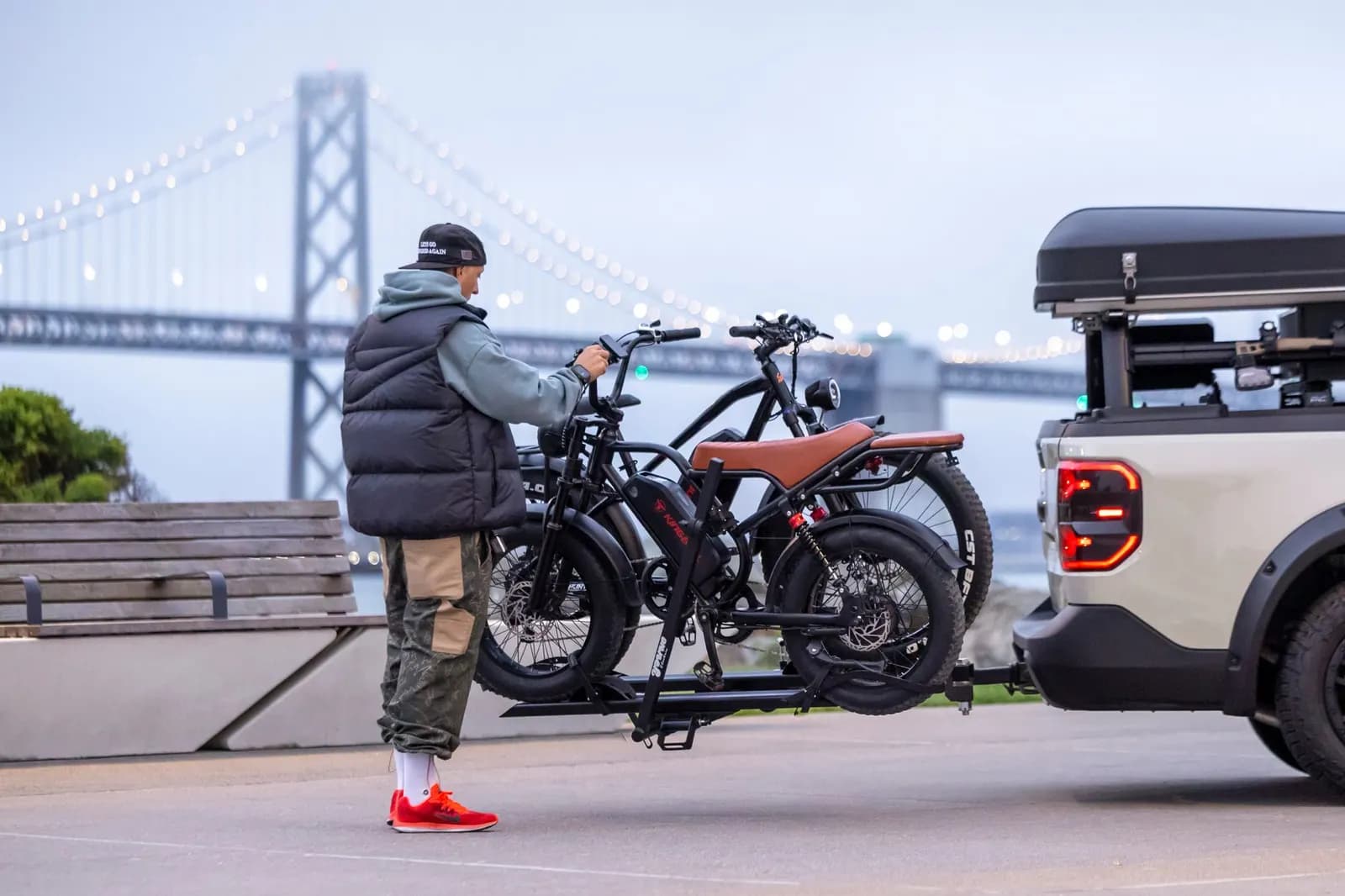 Iemand zet twee e-bikes op een fietsendrager op de trekhaak